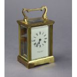 A brass-cased carriage clock with black roman numerals to the white enamel dial signed “GARRARD &