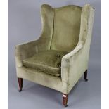 An Edwardian wing-back armchair upholstered cream velour, & on short square tapered legs with