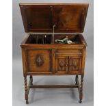 A 1930’s floor-standing gramophone in oak case enclosed by hinged lift-lid, & on short barley-