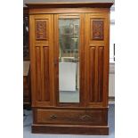 A late Victorian walnut wardrobe enclosed by a rectangular bevelled mirror door to centre flanked by