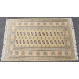 An Indian Bokhara rug of light yellow ground featuring two central rows of ghuls surrounded by