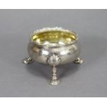 A George II silver large salt cellar of compressed round form with gadrooned rim, on three fluted