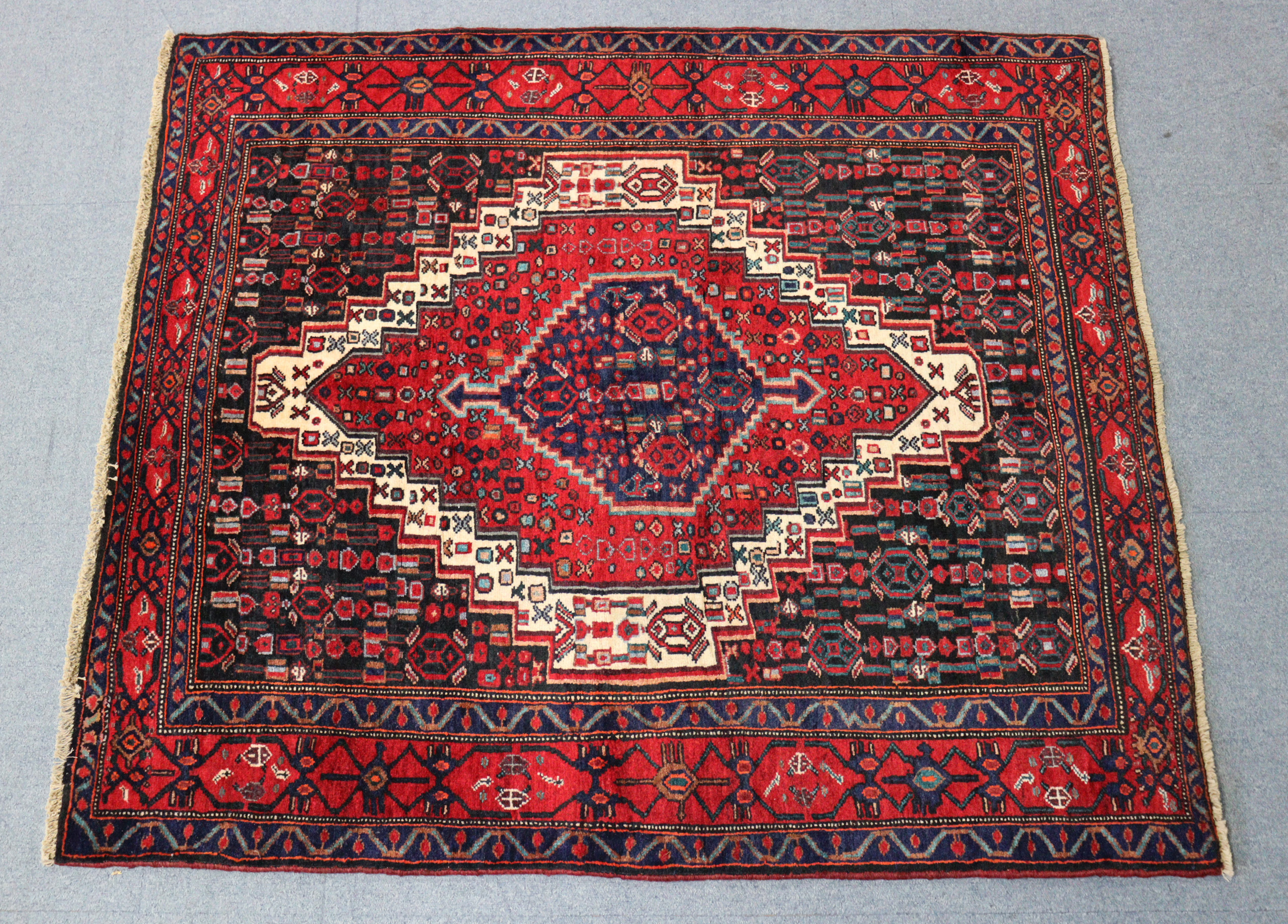 A North West Persian Senneh rug of indigo ground with a central medallion surrounded by geometric