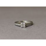 A DIAMOND RING, the princess cut stone set between a row of eight small round cut stones to each