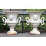 A PAIR OF HEAVY CAST-IRON GARDEN URNS, each with scalloped flared body, writhen serpent side