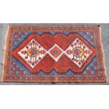 A Kazak rug of blue & madder ground featuring repeating multi-coloured geometric designs within