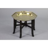 An oriental occasional table with octagonal engraved brass top, on folding hardwood “bamboo