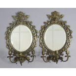 A pair of late 19th century oval girandoles, each with bevelled plate in foliate gilt-metal frame