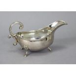 An Irish silver oval sauce boat with gadrooned rim, C-scroll handle, on three pad feet, 6¾” long;