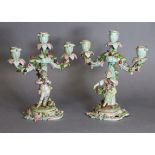 A pair of Meissen porcelain three-branch floral-encrusted candelabra, one with a girl holding a