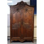 An 18th century carved oak armoire with an arched cornice centred by a wreath, billing doves,
