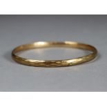 A 9ct gold (metal core) stiff bangle with faceted surface.