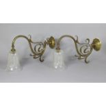 A pair of Art Nouveau oxidised brass wall-mounted gas lights, each with clear cut glass bell-