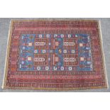 A Kazak rug of blue & madder ground featuring geometric floral designs within multiple narrow