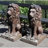 A pair of decorative fibre-glass models of recumbent lions, with painted black finish & on