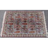 An antique Caucasian carpet of pale blue ground featuring repeating floral designs within two narrow