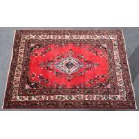 A Persian Lillihan carpet of crimson ground with central medallion surrounded by floral motifs, in
