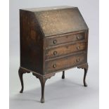 A mid-20th century oak bureau with a fitted interior enclosed by a fall-front above three long