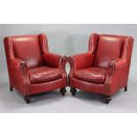 A pair of McKinley (American) brass-studded crimson leather wing-back armchairs on carved & turned