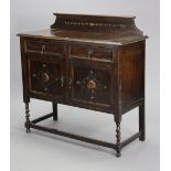 A mid-20th century small oak sideboard with a low-stage panel back, fitted two frieze drawers