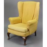 A mid-20th century wing-back armchair with yellow loose covers, & on short cabriole legs & pad feet.