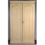 A Victorian pine wardrobe with a moulded cornice, having a fitted interior enclosed by pair of panel