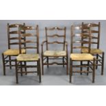 A matched set of five ladder-back dining chairs (including on carver), each with a woven-rush