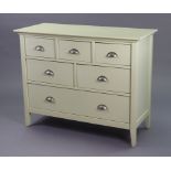 A white-finish low chest fitted with an arrangement of five short & one long drawer, & on short
