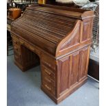 A teak roll-top desk with a fitted interior enclosed by a tambour shutter, & fitted four long