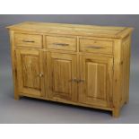 A light oak sideboard fitted three frieze drawers above cupboards enclosed by three fielded panel