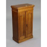 A small oak cupboard fitted three shelves enclosed by a pair of panel doors, & on a plinth base,