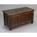 A 17th century & later oak coffer with a hinged lift-lid, with a carved & panel front, & with