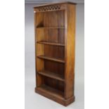A hardwood tall standing open bookcase with a pierced frieze, fitted four shelves, & on a plinth