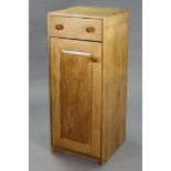 A light elm upright cupboard fitted frieze drawer above two shelves enclosed by a panel door, 17¾”