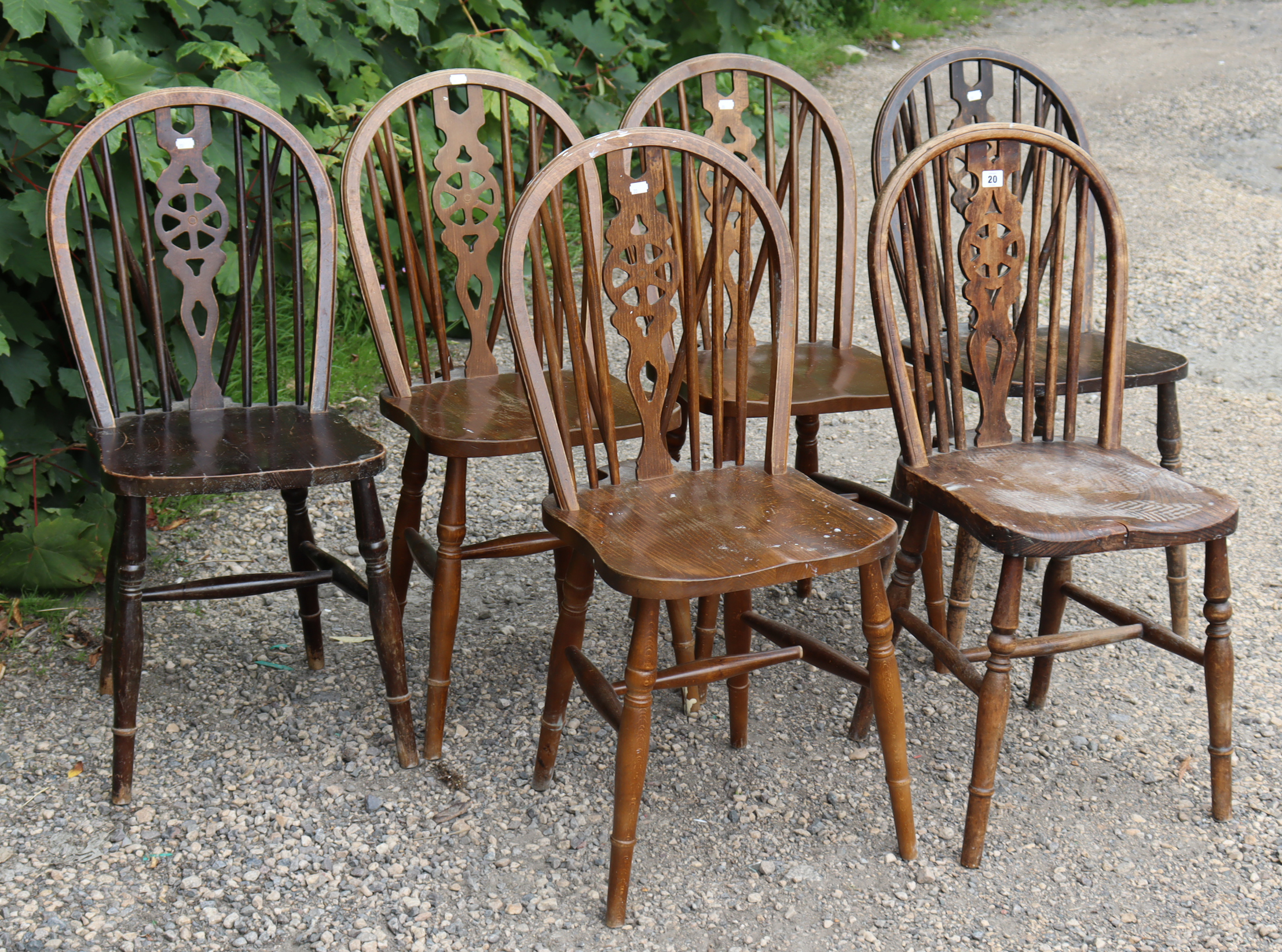 A set of six wheel-back dining chairs with hard seats, & on turned legs with spindle stretchers.