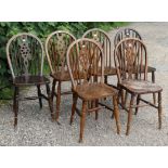 A set of six wheel-back dining chairs with hard seats, & on turned legs with spindle stretchers.