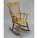 A lath-back rocking chair with a hard seat, & on turned supports.