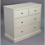 A white-finish low chest fitted two short & two long drawers with nickel knob handles, & on a plinth