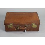 A vintage tan leather suitcase fitted brass twin-lever locks, 25½” wide x 8” high x 16” deep.