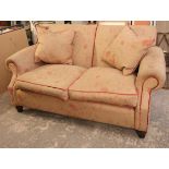 A John Sankey two-seater settee with loose cushions to the seat upholstered cream & multi-coloured