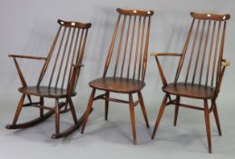 An Ercol spindle-back rocking chair with hard seat, & two similar dining chairs.
