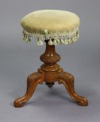 A Victorian carved walnut piano stool with a padded revolving seat, & on a vase-turned centre column