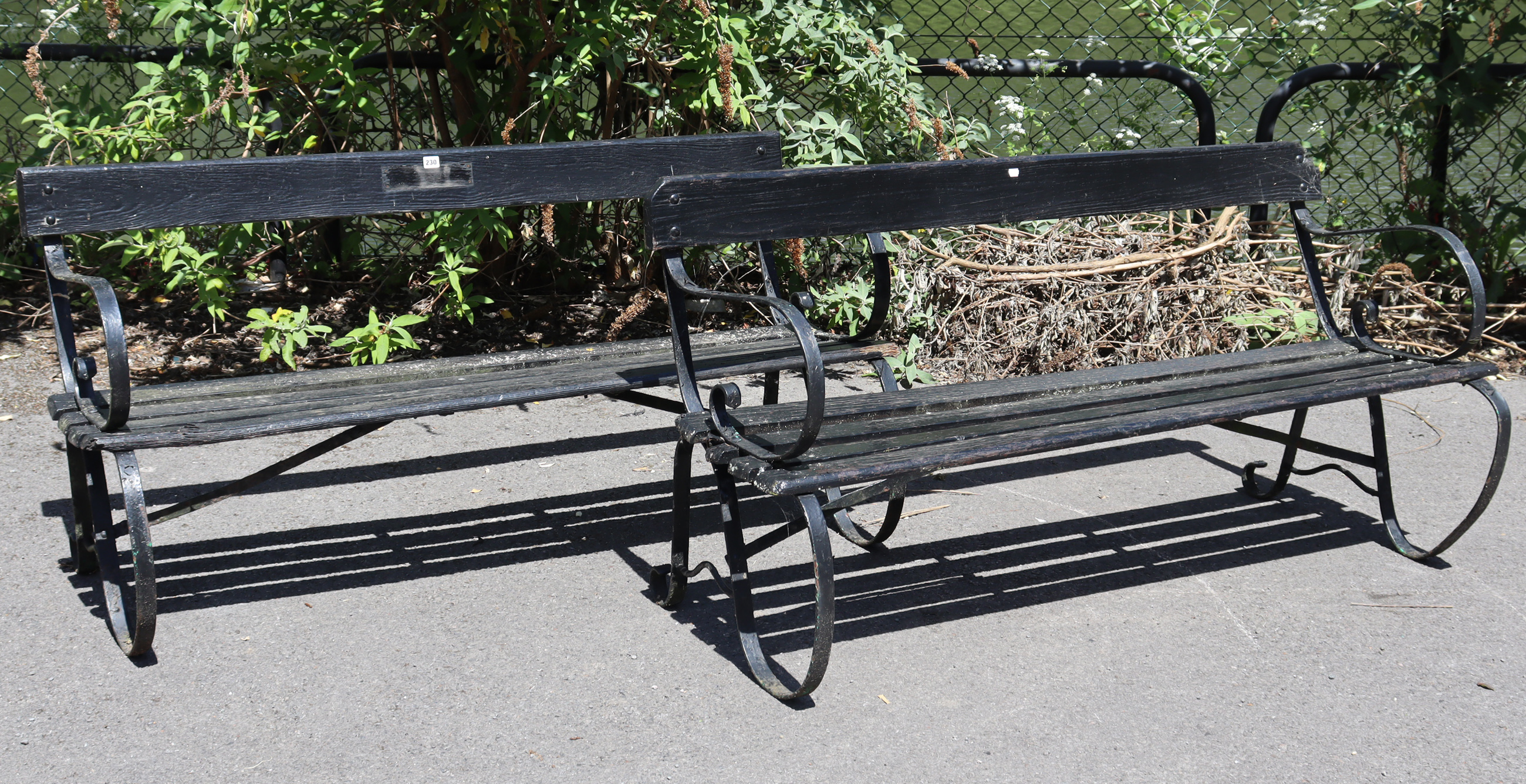 A pair of black painted wrought-iron & wooden slated garden benches (slight faults), 50” long.