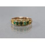 An antique gold ring set row of five graduated rectangular-cut foil-backed emeralds, with scroll