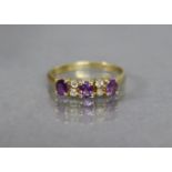 An amethyst & diamond ring, the three oval amethysts with pairs of small white stones in between,