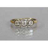 An 18ct. gold & platinum ring set three small diamonds within open circles, tiny rose diamonds in