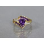 An amethyst & diamond ring of cross-over design, the triangular-cut amethyst between split shoulders