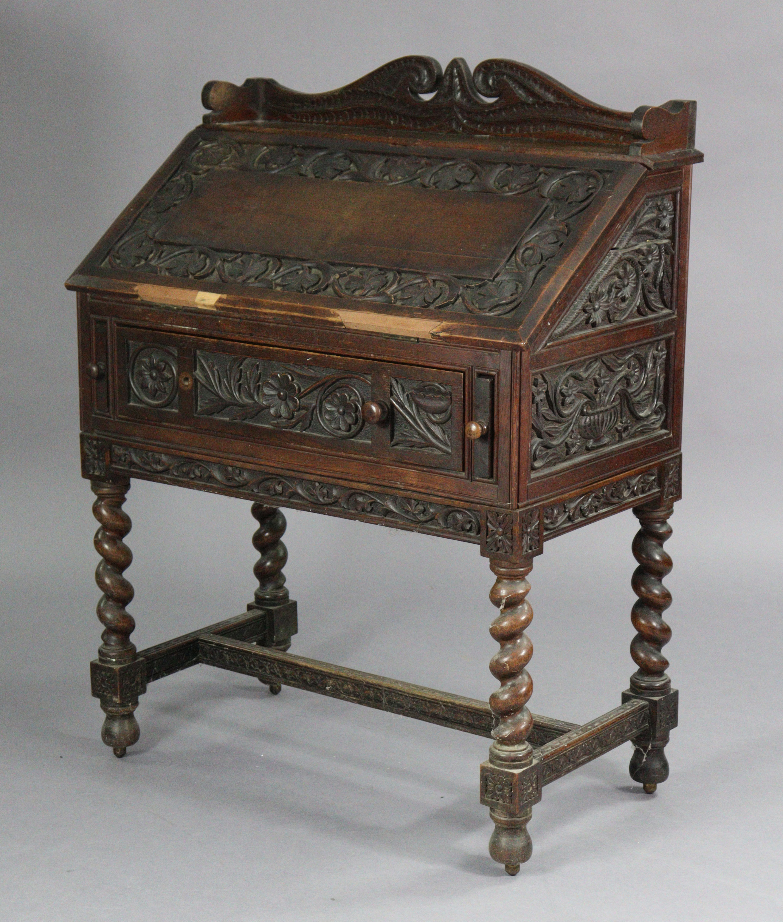 An early 20th century carved oak bureau, with shaped tray-top above a fitted interior enclosed by