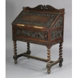 An early 20th century carved oak bureau, with shaped tray-top above a fitted interior enclosed by