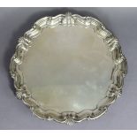 A George V silver salver with raised shell-&-scroll border, on three acanthus scroll feet, 10¼”